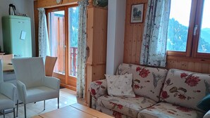 A living room with a wooden table, a floral sofa, and a green cabinet. - Magnificent panorama (Le Biot)
