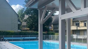 Un espace extérieur abrité avec une piscine, un sol carrelé et une structure en forme de pergola.