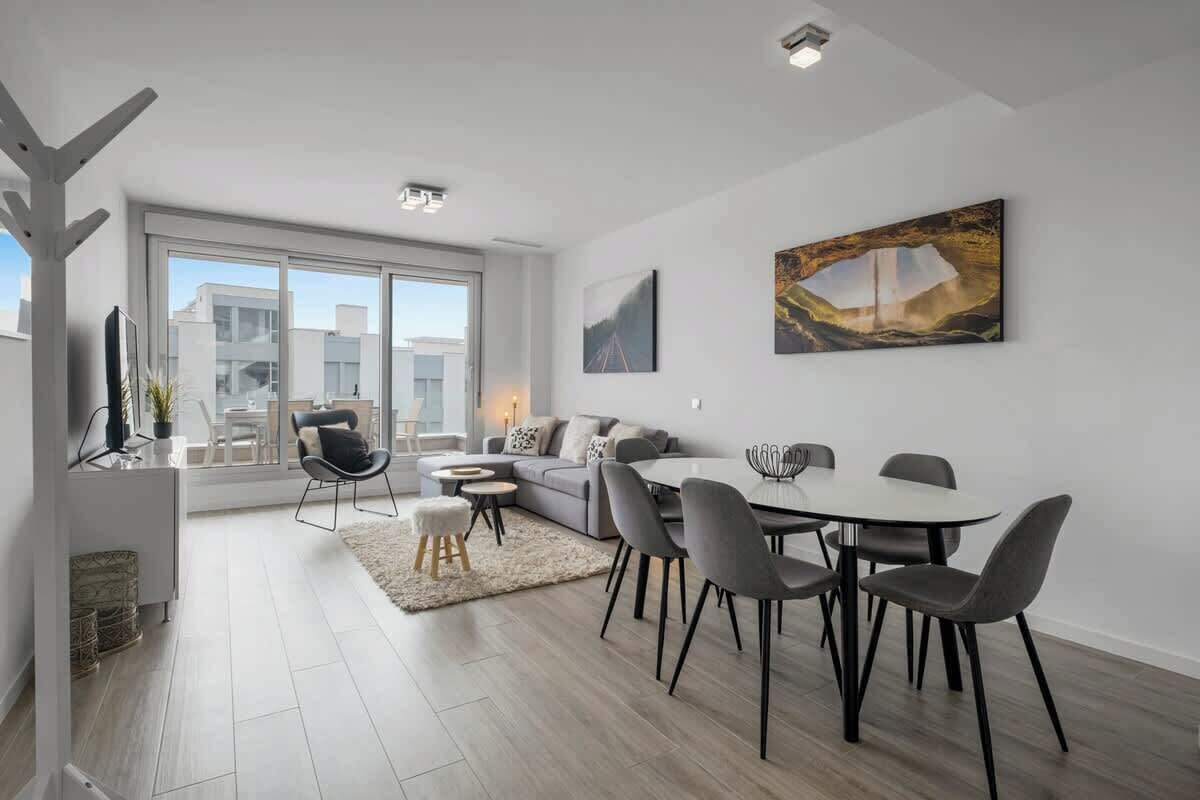Un salon moderne avec un coin repas, de grandes fenêtres et des œuvres d’art accrochées aux murs.