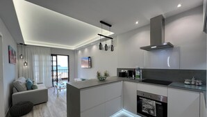 A modern kitchen with a central island, built-in oven, and a dining area with a view of the sea. - Boutique one bed sea views free wifi (Arona)