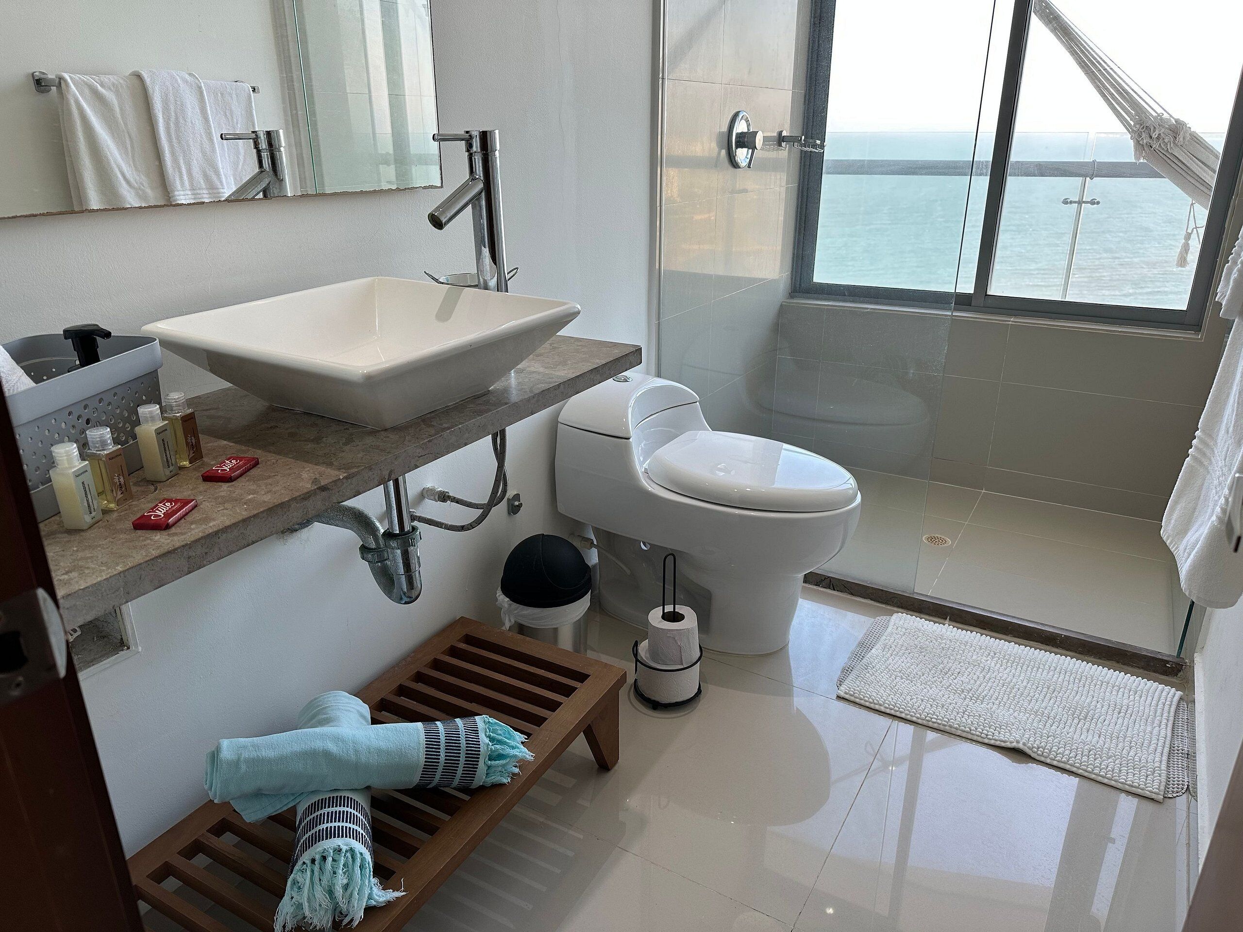 A modern bathroom with a large sink, toilet, and a glass-enclosed shower.
