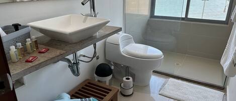 A modern bathroom with a large sink, toilet, and a glass-enclosed shower.