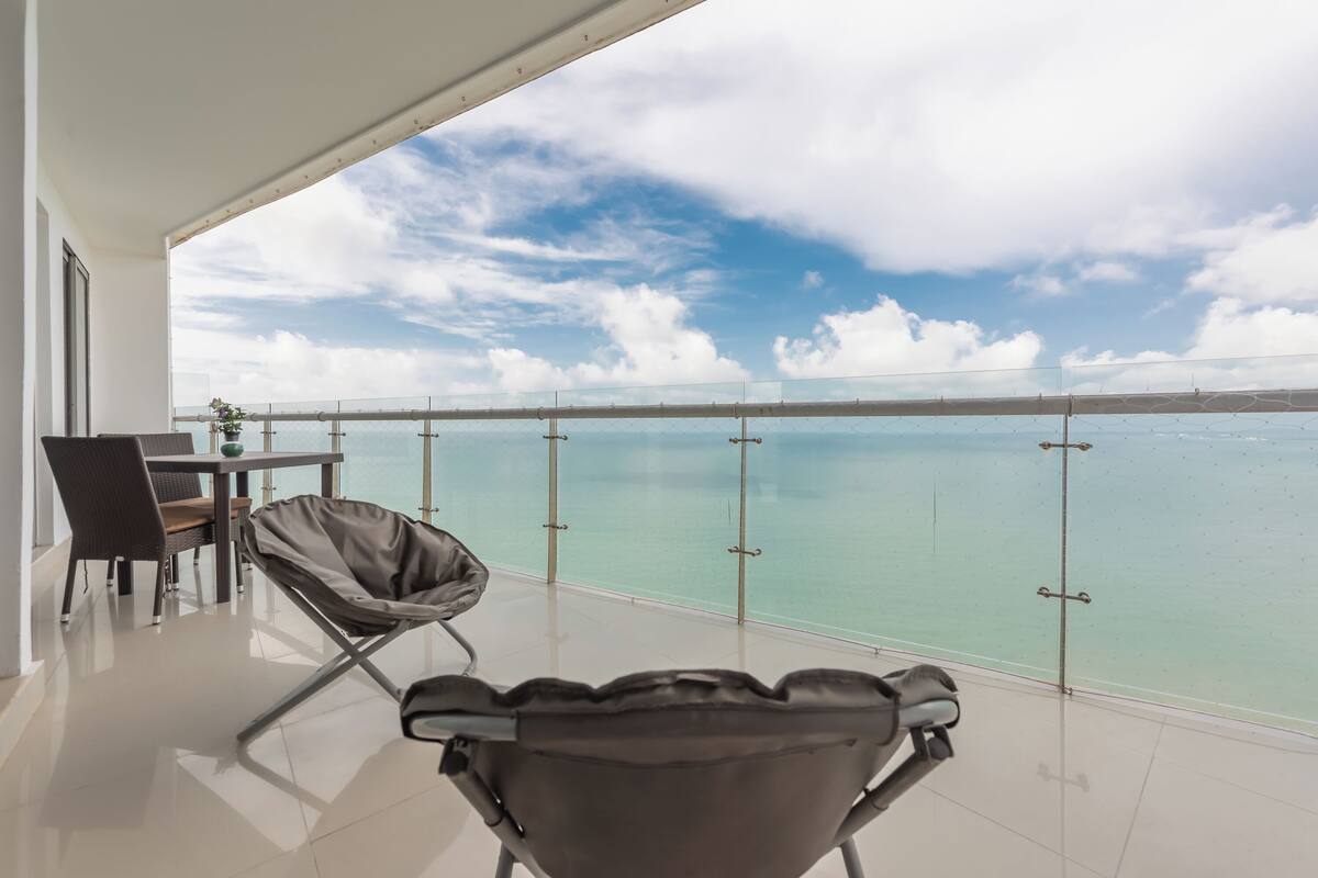 Een balkon met uitzicht op zee, een stoel, een tafel en een plant.