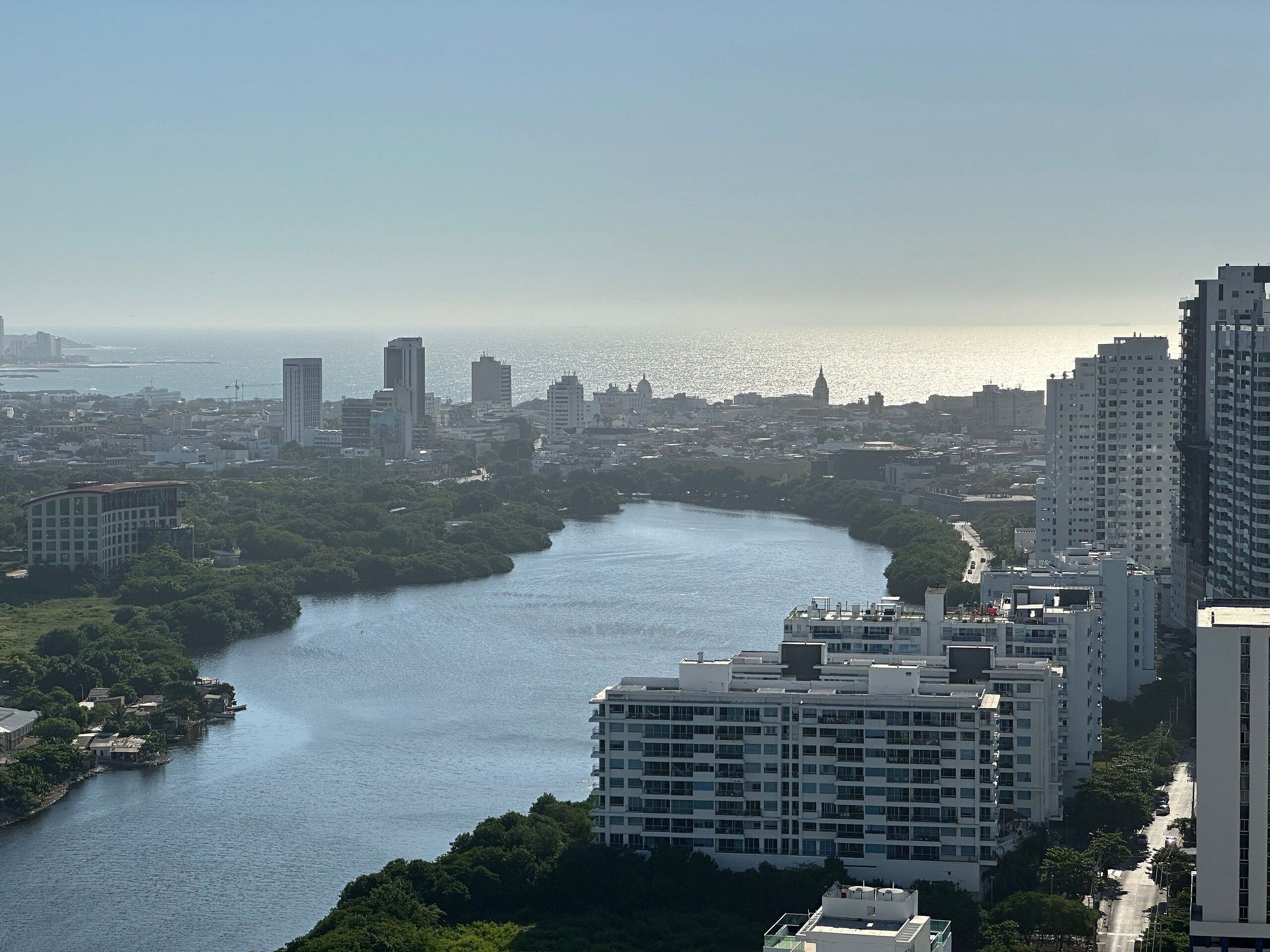 A river winding through a city with modern buildings and a clear sky.
