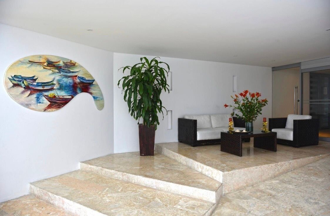 A lobby with a large abstract painting, a potted plant, and a seating area with two sofas and a coffee table.