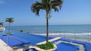 A pool area with a palm tree and a view of the ocean. - Edificio Alta Mar de Marbella (Cartagena)