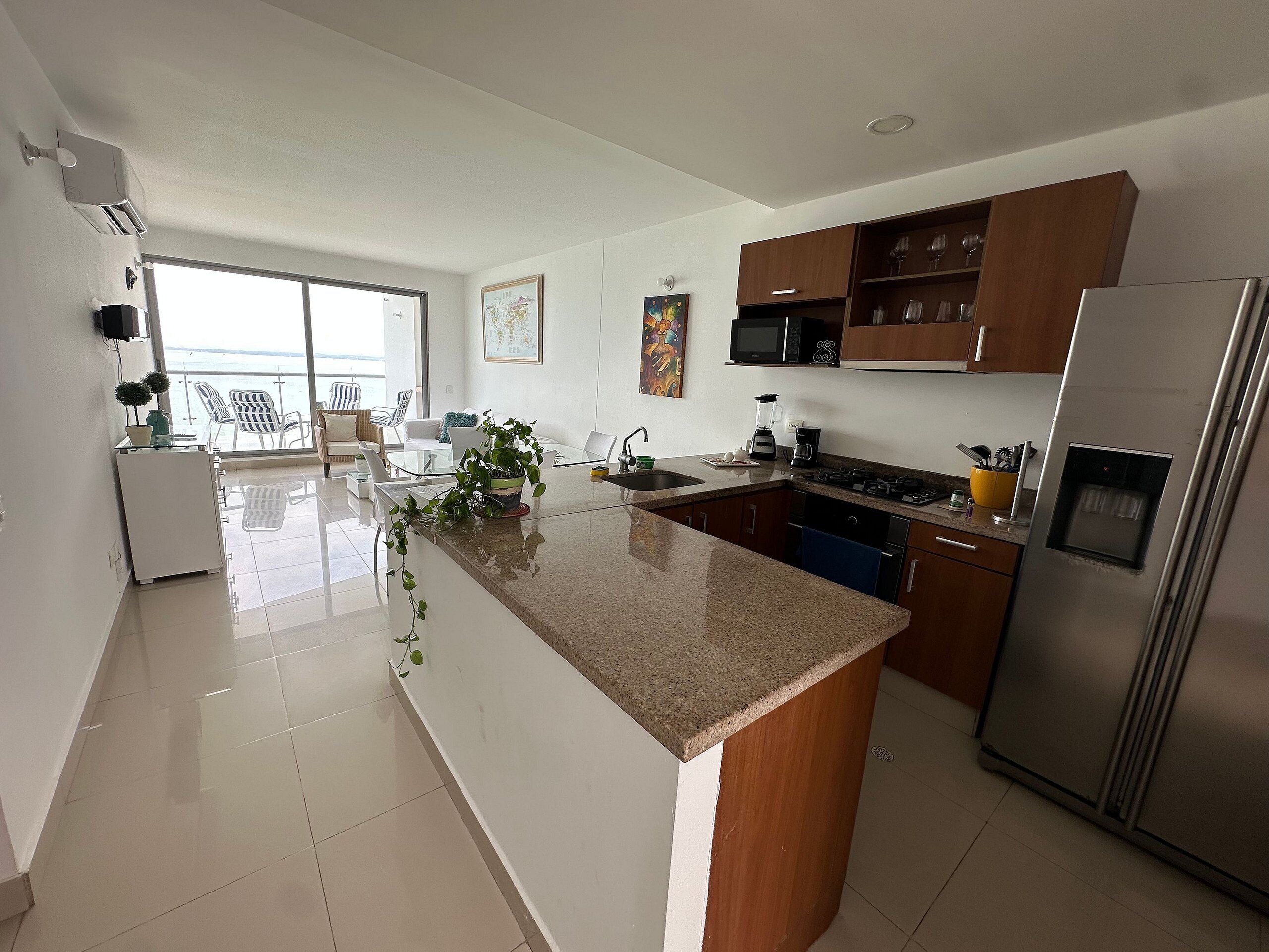 Cozinha moderna com ilha central, eletrodomésticos de aço inoxidável e vista para o exterior.