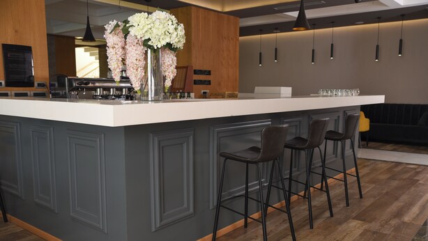 A modern kitchen with a large island, bar stools, and pendant lighting. - Hotel Albulena (Mamurras)