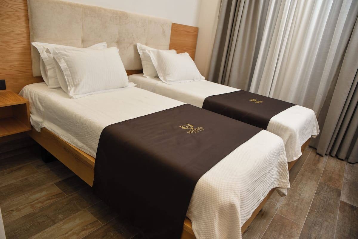 A hotel room with two beds, wooden headboards, and a nightstand.