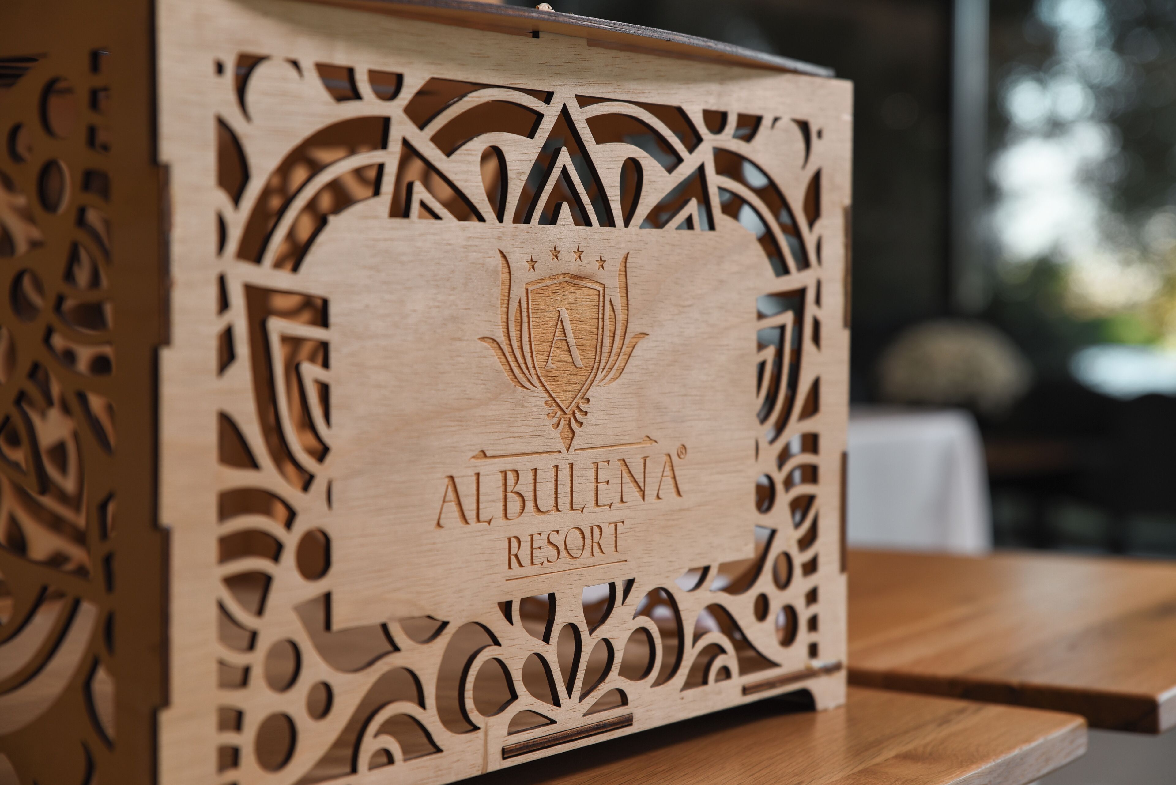 A wooden box with intricate cut-out patterns and the text "ALBULENA RESORT" prominently displayed.