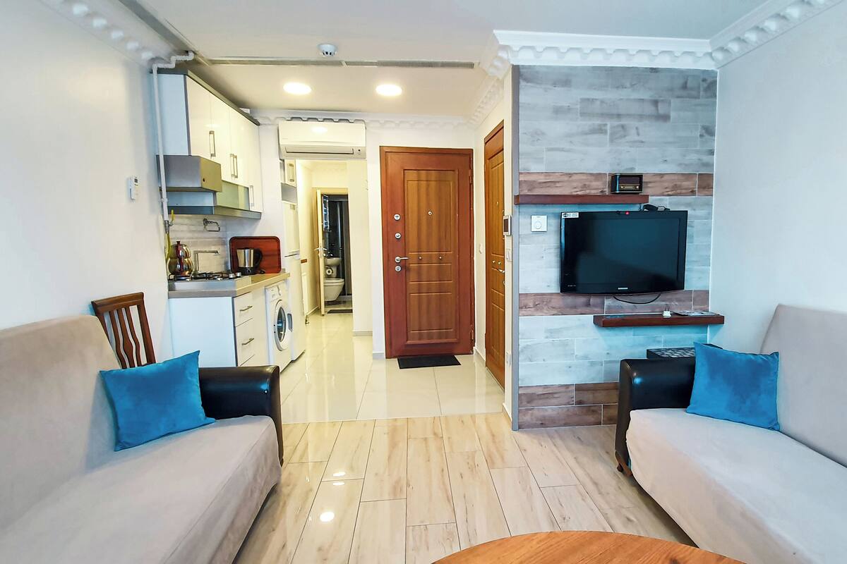 A modern living room with a sofa, a coffee table, and a TV mounted on a stone wall.