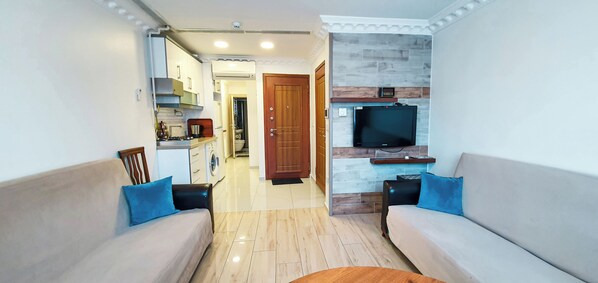 A modern living room with a sofa, a coffee table, and a TV mounted on a stone wall.