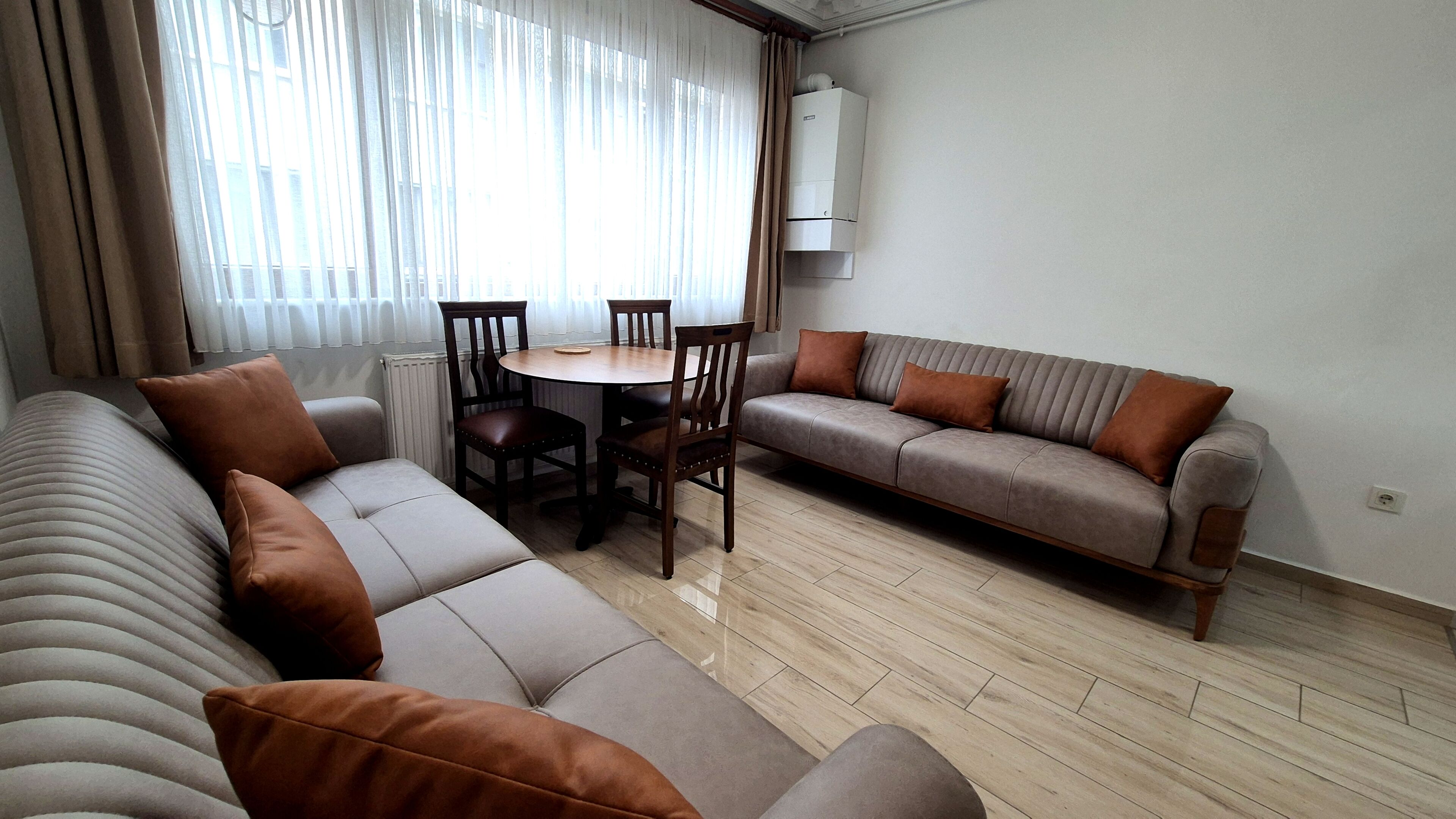 A modern living room with a sofa, a dining table with chairs, and a built-in air conditioning unit.