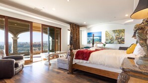 Un dormitorio espacioso con una cama grande, vistas a la ciudad y un balcón.
