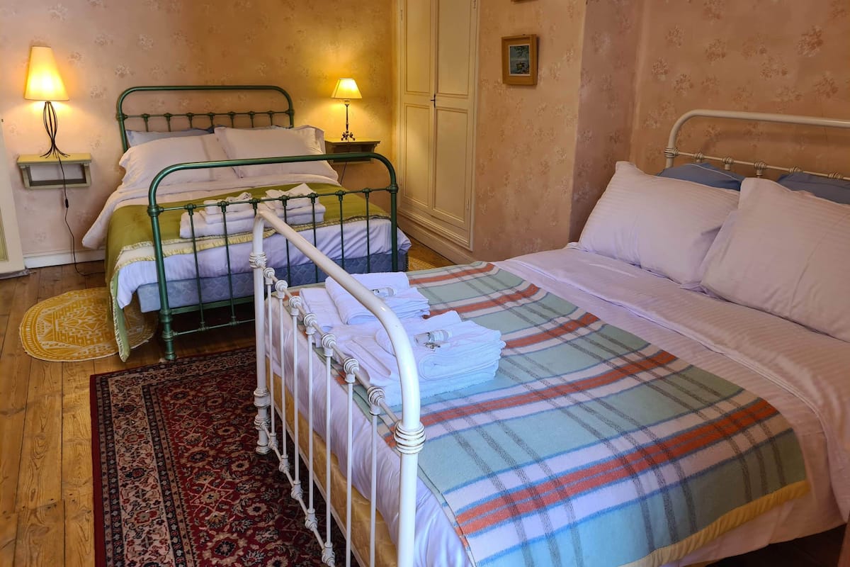 A bedroom with two beds, a wardrobe, and two bedside lamps.