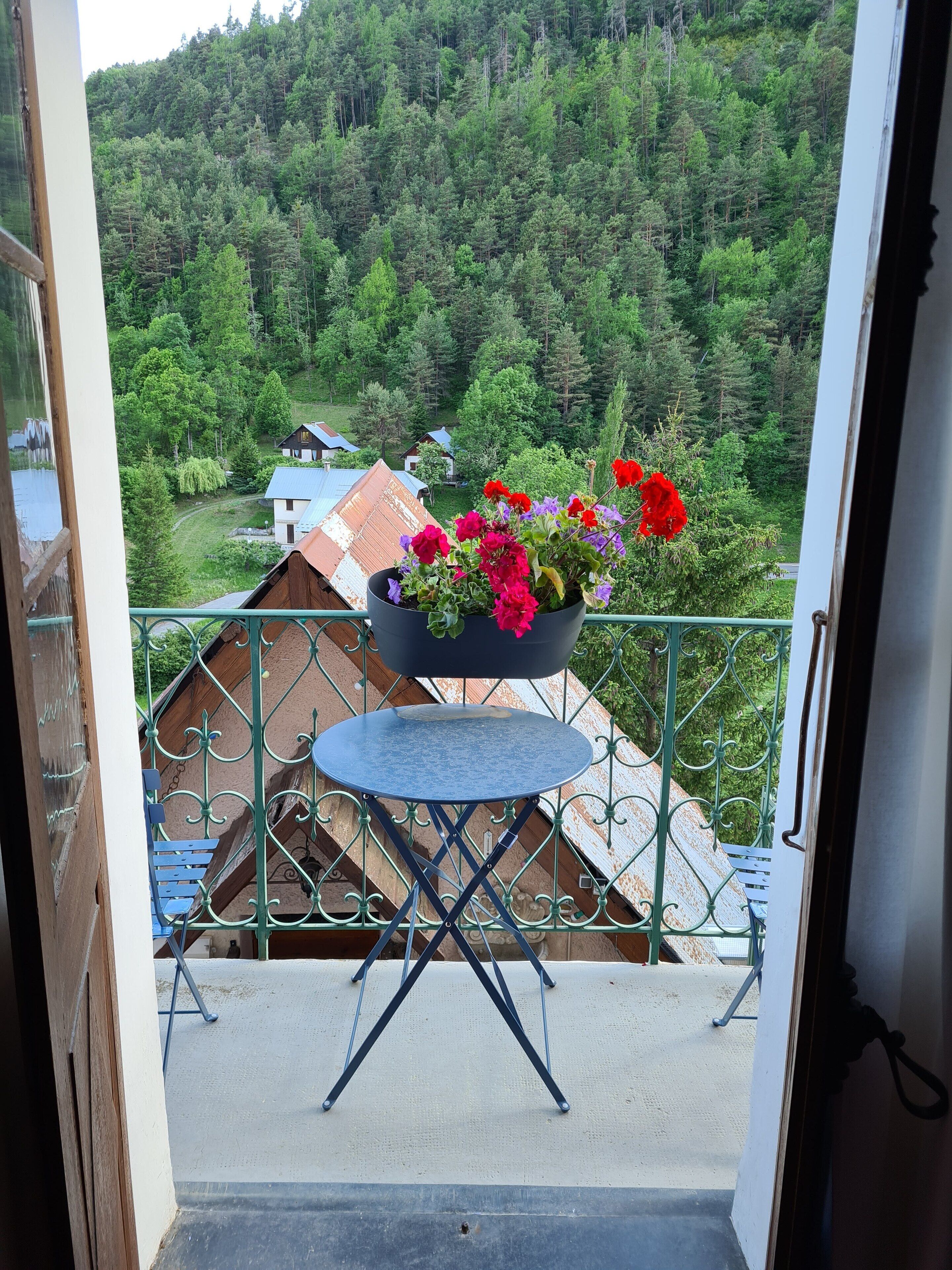 Ein Balkon mit blauem Tisch und einem Blumentopf.