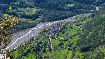 A rural village with houses clustered along a winding road, surrounded by lush greenery and hills.