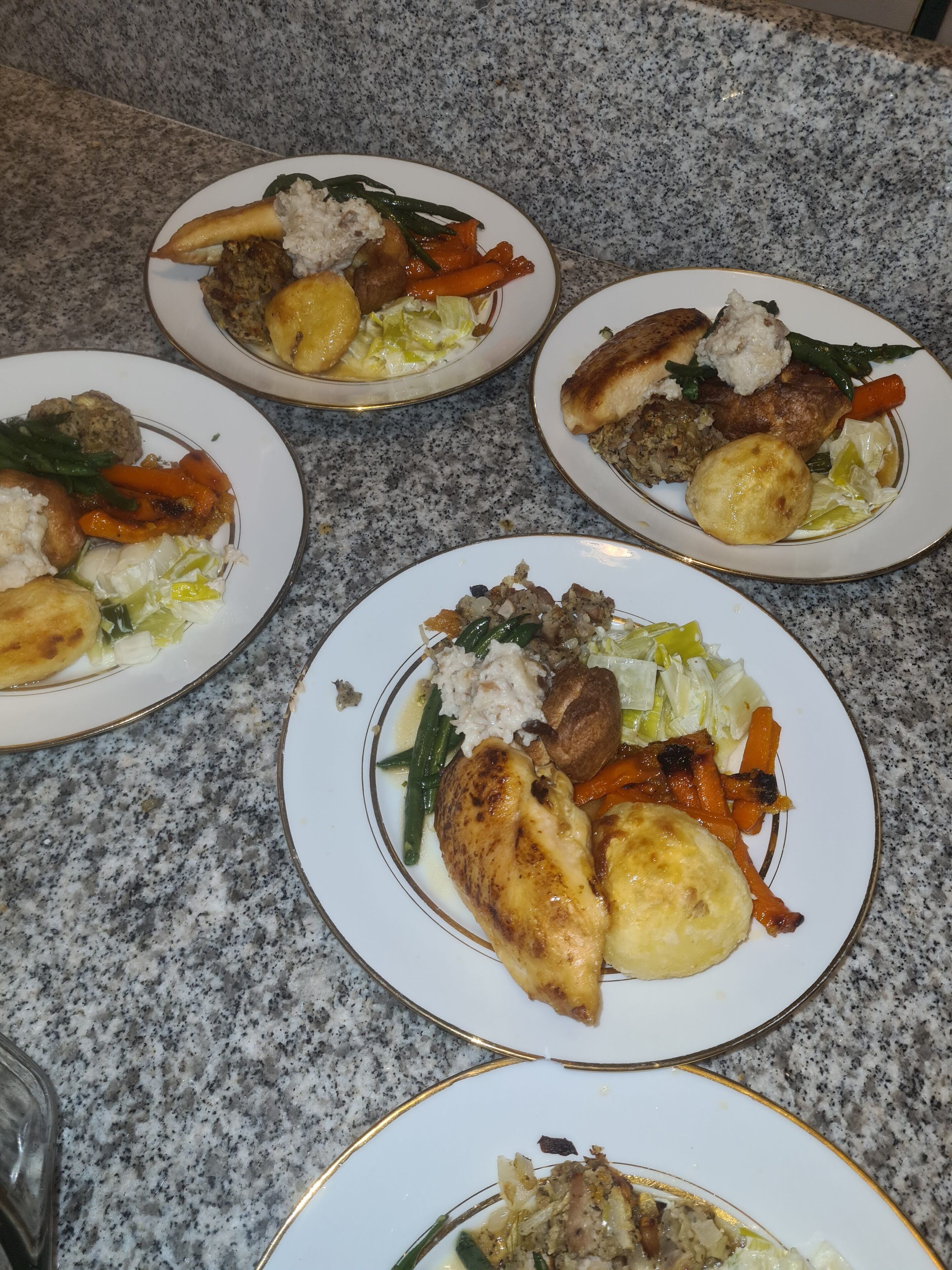 Four plates of food on a granite countertop.