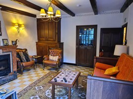 Uma sala de estar aconchegante com lareira, um armário de madeira, um candelabro e um chão quadriculado.