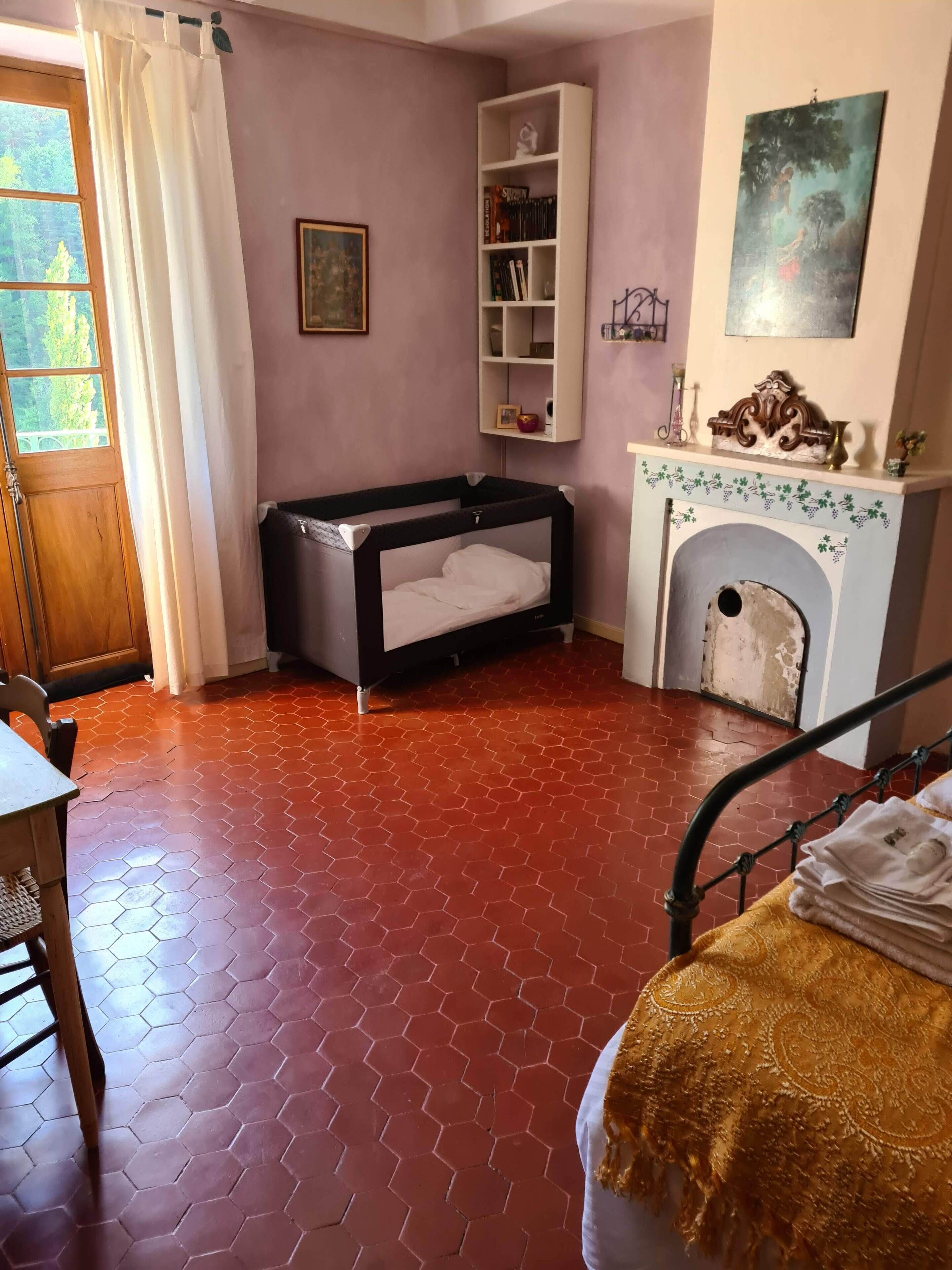 A room with a bunk bed, a fireplace, a bookshelf, and a window with curtains.