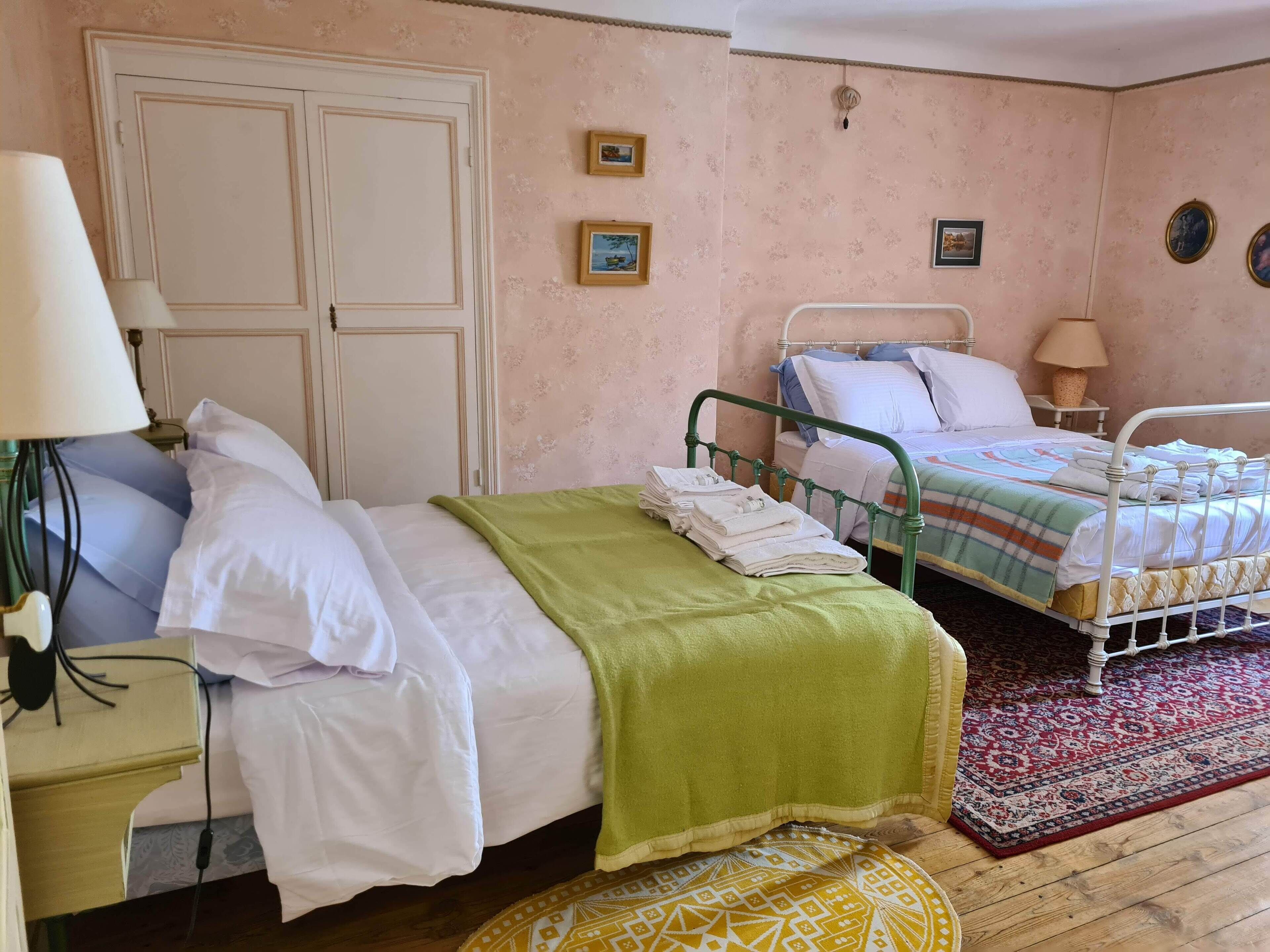 Un dormitorio con dos camas, una mesita de noche con lámpara y una puerta.
