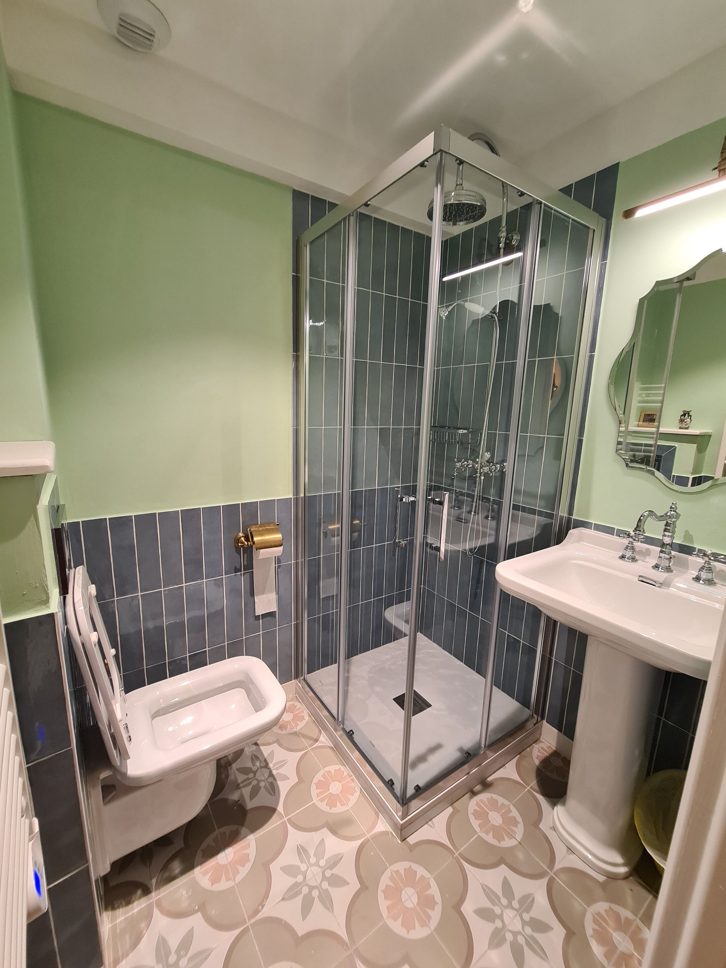 A bathroom with a glass-enclosed shower, a white sink, and a toilet.