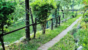 A pathway through a lush, green park with trees and a gravel path.