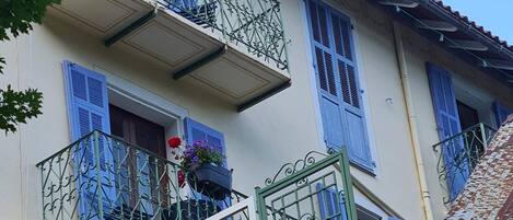 A multi-story building with balconies, blue shutters, and flower boxes.