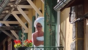 Un balcó amb una persona en tovallola, un gos i un cartell que diu "HOTEL".