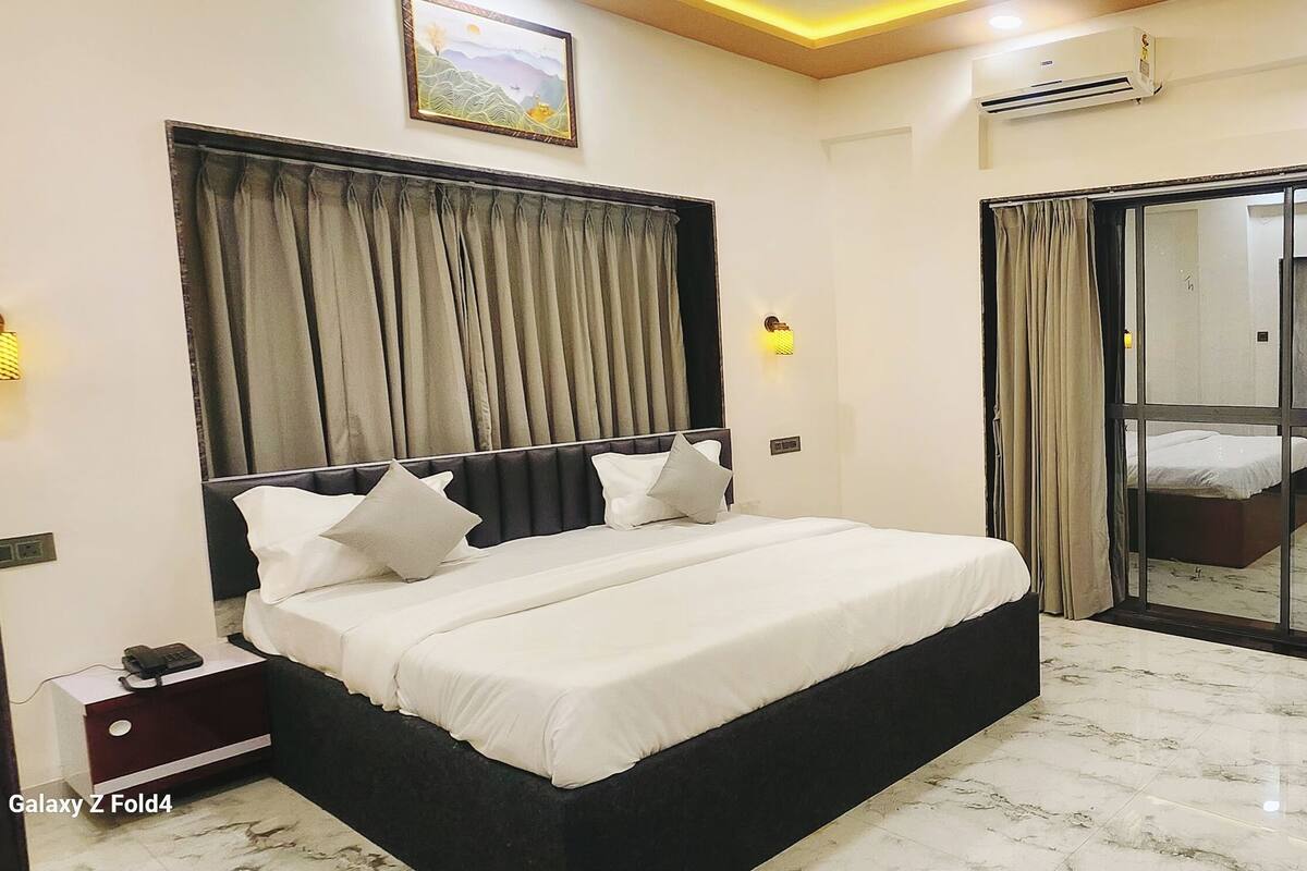 A hotel room with a bed, a desk, a mirror, and a sliding door.