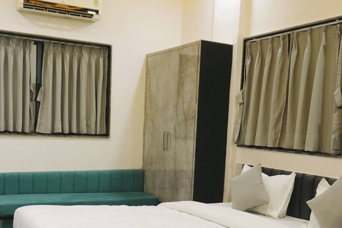 A bedroom with a bed, a wardrobe, a bench, and curtains.