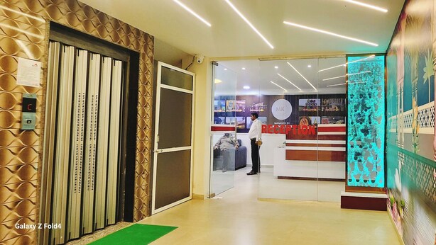 A reception area with a modern design, including a reception desk, a security camera, and a glass partition. - Hotel Sahara Residency (Nashik)
