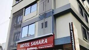 A multi-story hotel named "Hotel Sahara" with a modern facade, large windows, and a sign indicating management by M.K. Hospitality. - Hotel Sahara Residency (Nashik)