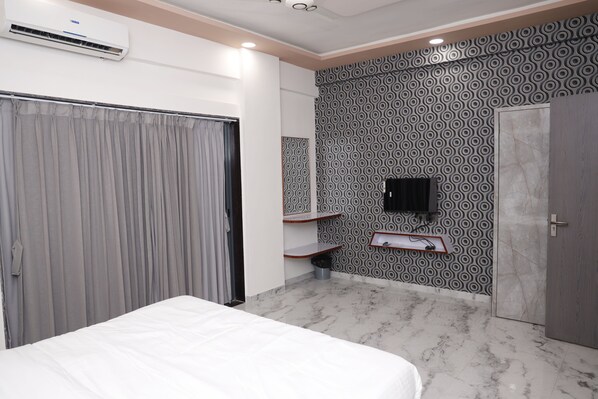 A hotel room with a bed, a wardrobe, a mirror, a TV, and a patterned wall.