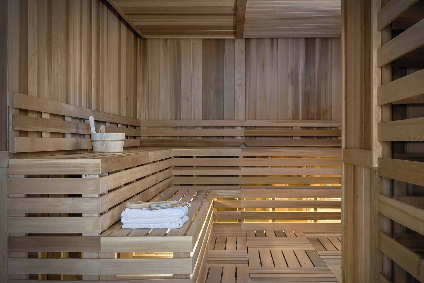 En sauna med træbænke og en bænk med håndklæder.