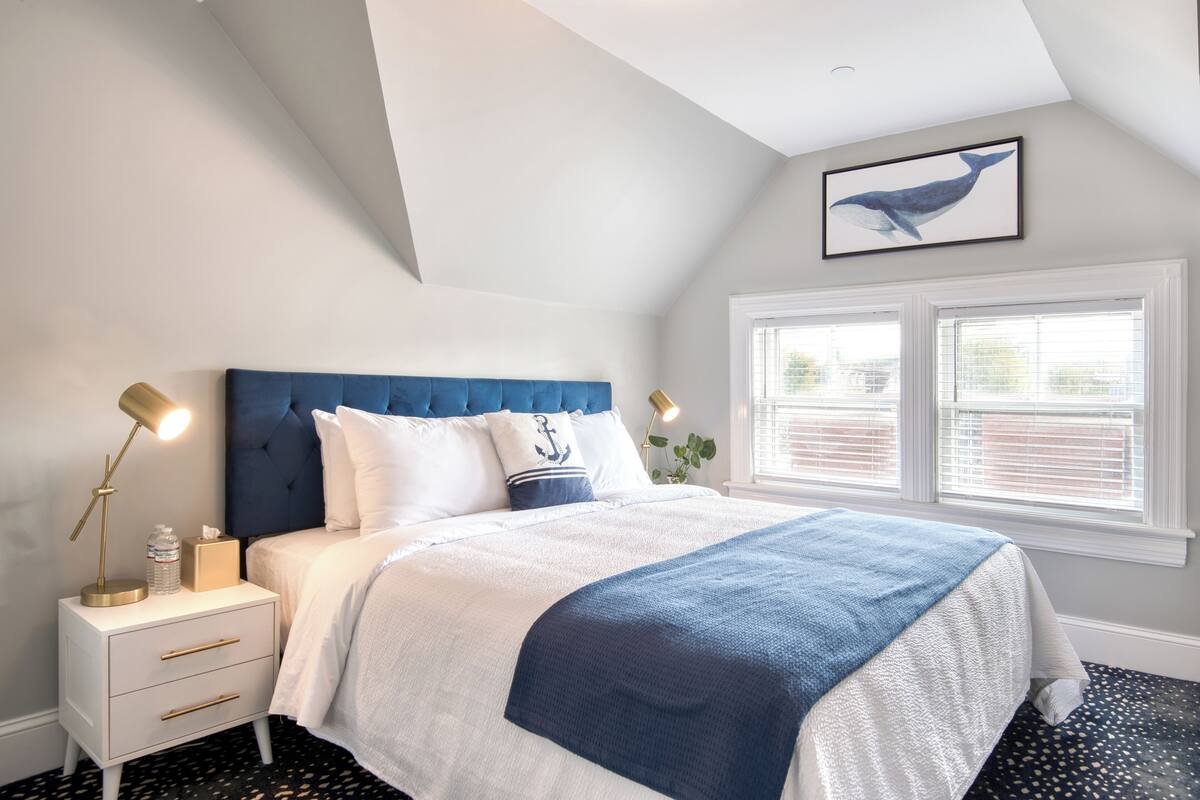A bedroom with a bed, nightstand, lamp, and window.