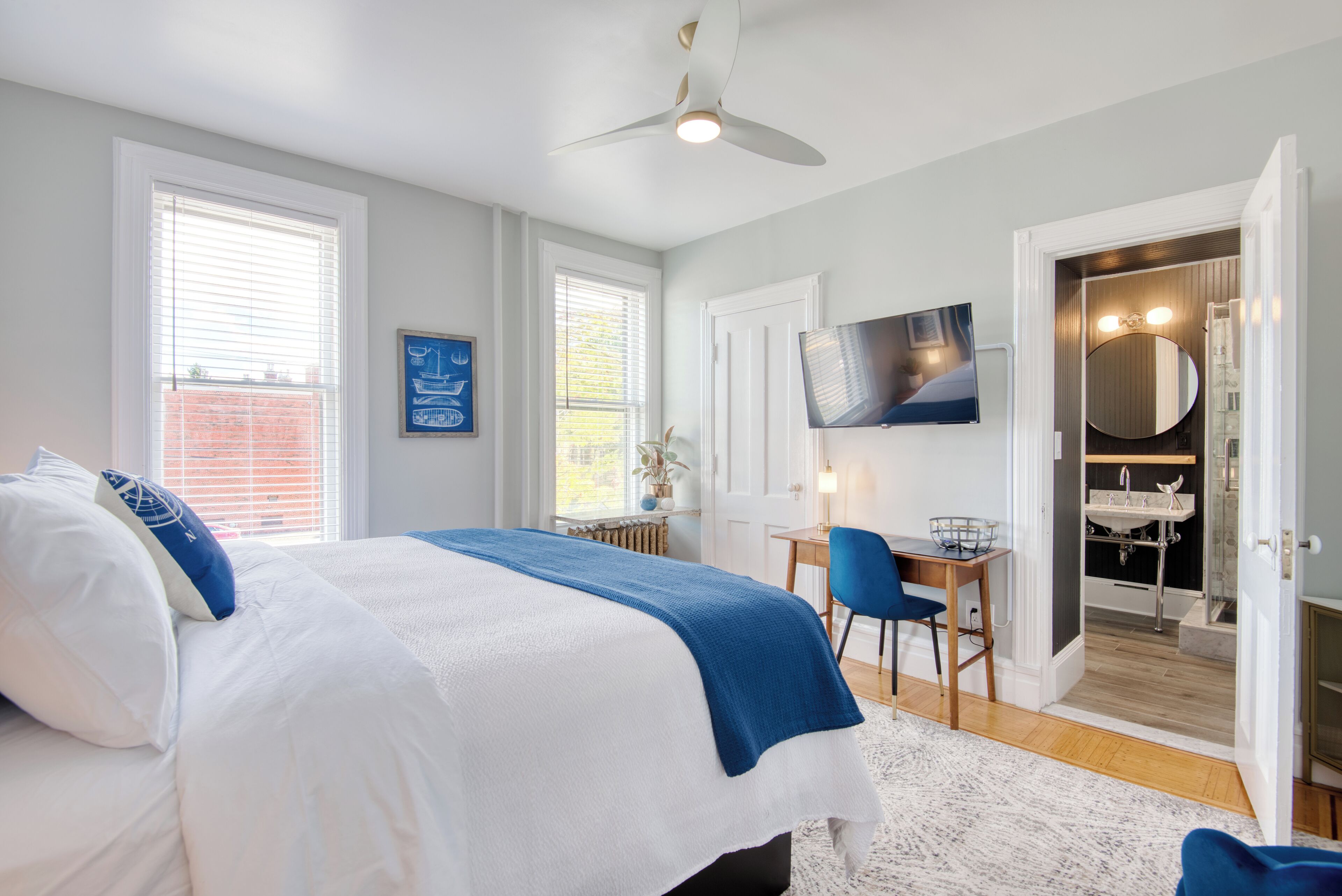 A bedroom with a large bed, a desk, and a bathroom visible through an open door.