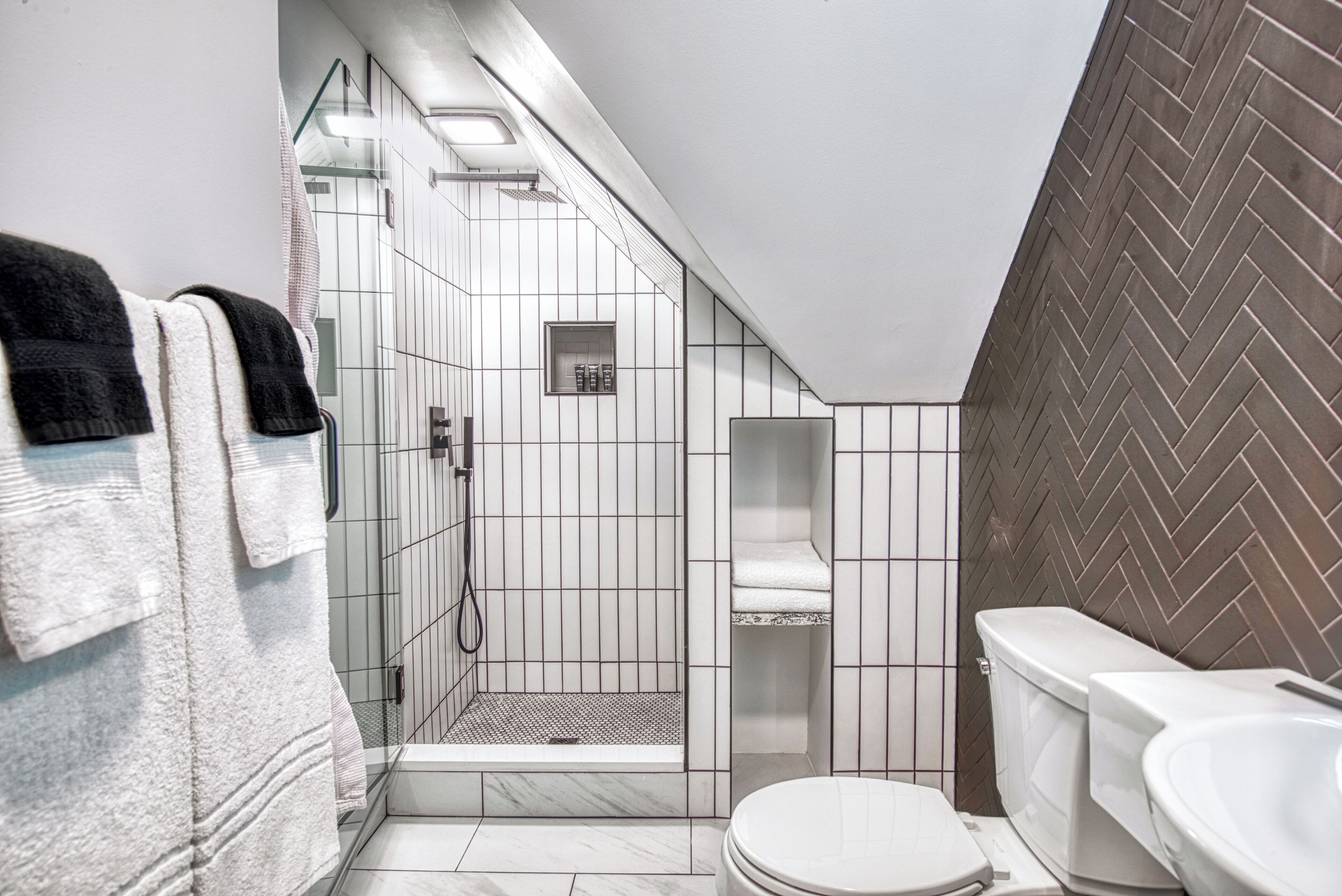 A modern bathroom with a shower, toilet, and towel rack.
