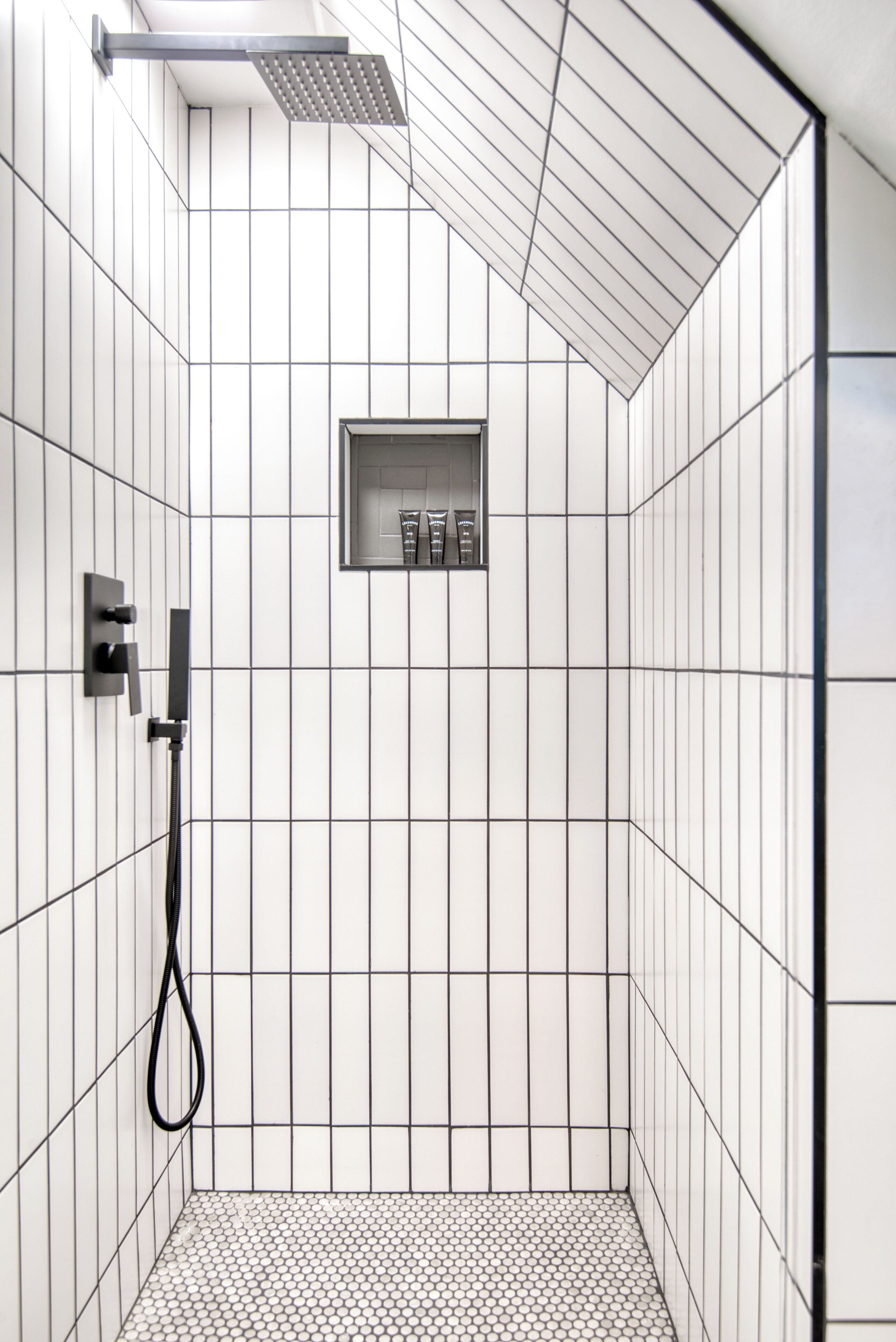 A modern shower with a rectangular showerhead and a handheld shower attachment.
