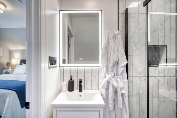 A modern bathroom with a white sink, a large mirror, and a glass shower enclosure.