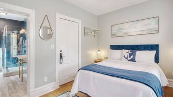 Quarto com cama, porta, prateleira na parede e um quadro.