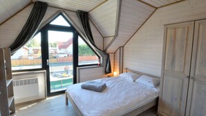 A bedroom with a bed, a wardrobe, and a window with curtains. - Holiday Home With Terrace, Sauna (Ustronie Morskie)
