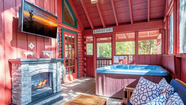 Un intérieur de chalet chaleureux avec une cheminée en pierre, un bain à remous et un coin salon confortable.