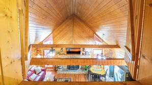 Un intérieur en bois avec un plafond en pente, une cheminée, un canapé et un coin repas.
