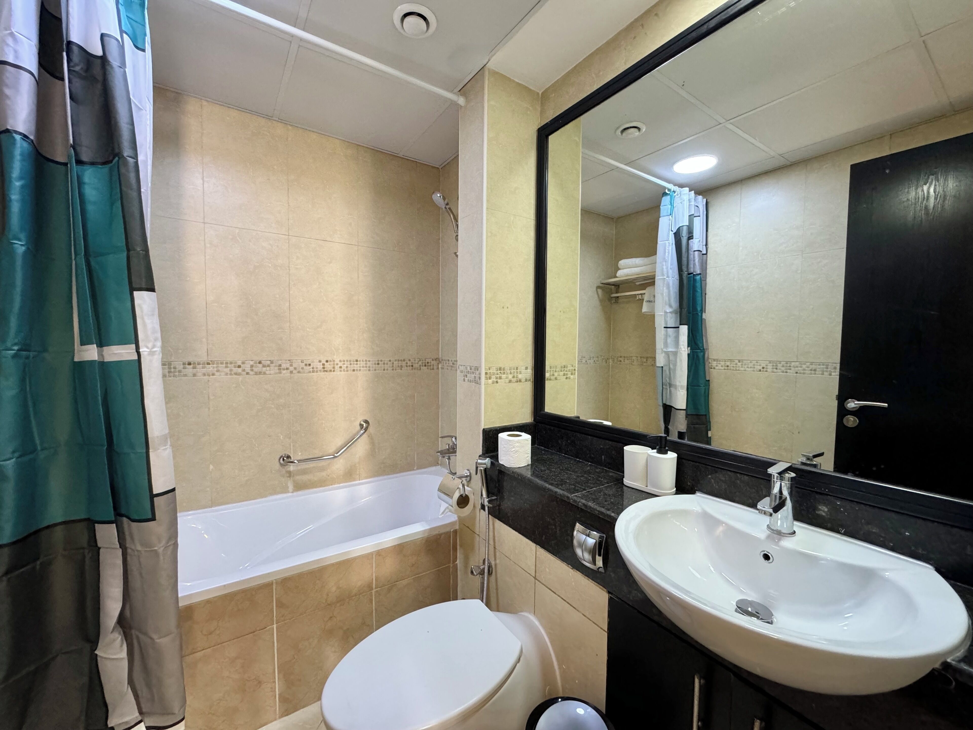 Un baño con bañera, inodoro, lavabo y un espejo grande.
