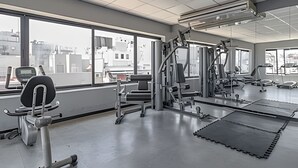 A gym with various exercise equipment, large windows, and a view of buildings outside. - Comfy Studio in Recoleta with Pool & Gym (Buenos Aires)