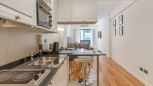 A modern kitchen with white cabinets, stainless steel appliances, and a central island with bar stools. - Comfy Studio in Recoleta with Pool & Gym (Buenos Aires)