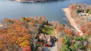 An aerial view of a lakeside property with a house, dock, and surrounding trees. - Cozy Lake Retreat w/ Dock, Fire Pit & Views (Oakland)
