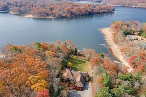 An aerial view of a lakeside property with a house, dock, and surrounding trees. - Cozy Lake Retreat w/ Dock, Fire Pit & Views (Oakland)