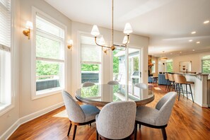 Un coin repas comprenant une table ronde en verre, quatre chaises et un lustre.